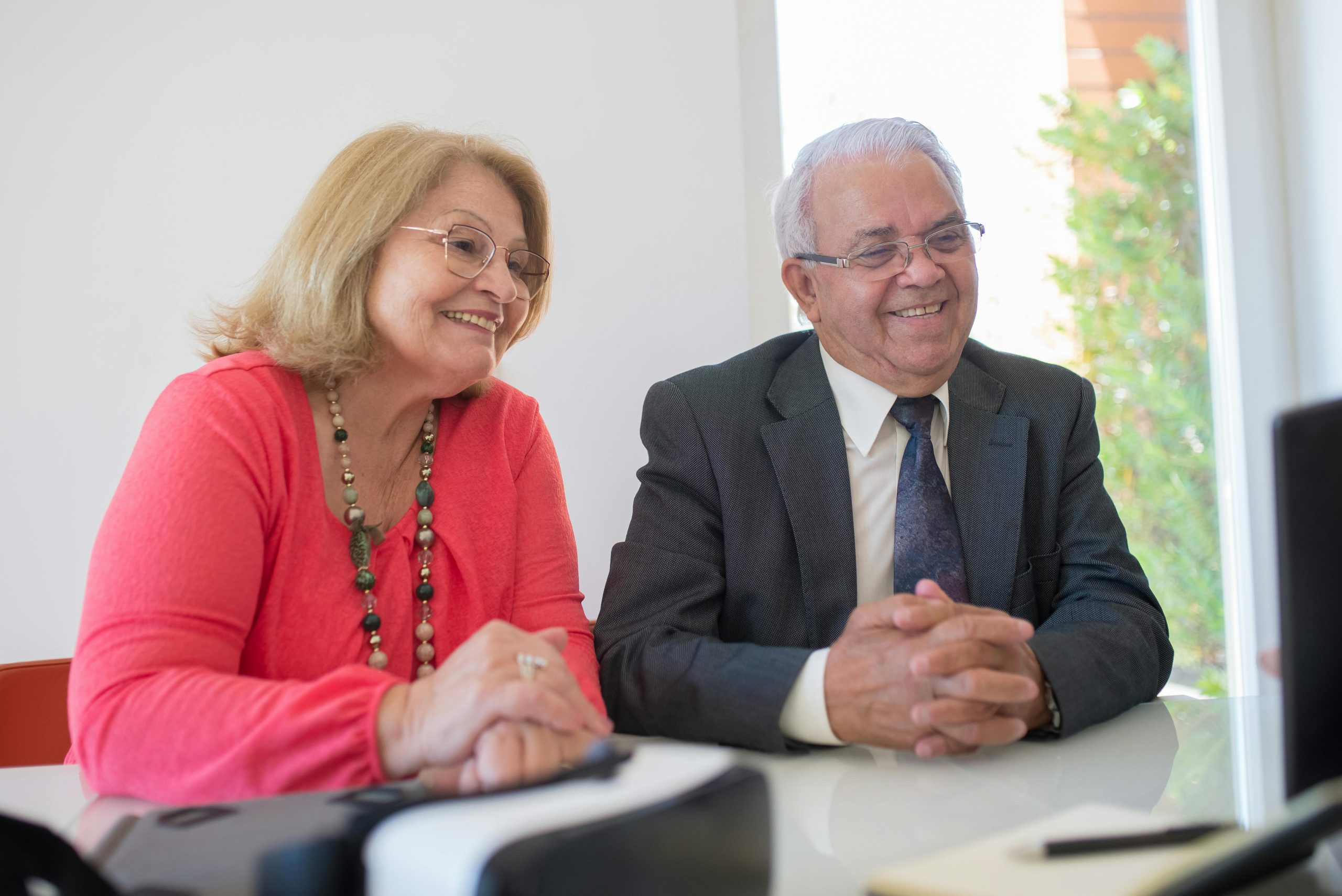 Two older people sit at a table discussing wills and estate planning with a lawyer.